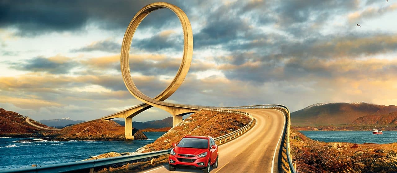 Red car driving on the road by the river