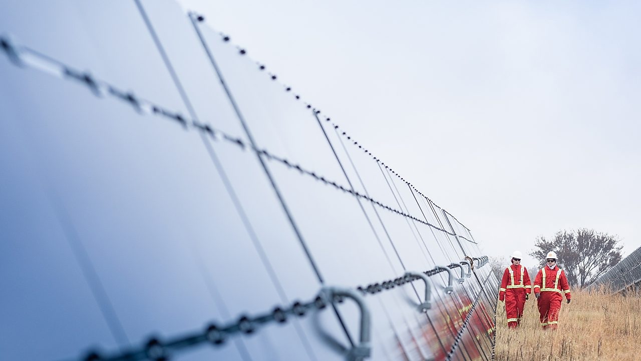 Two Shell employees walking between massive solar panels