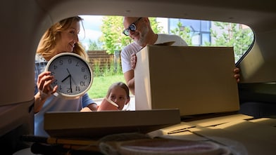 Family unloading boxes and a clock from a car trunk.
