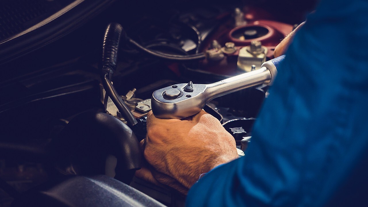 Mechanic’s hand tightening an engine part with a wrench.
