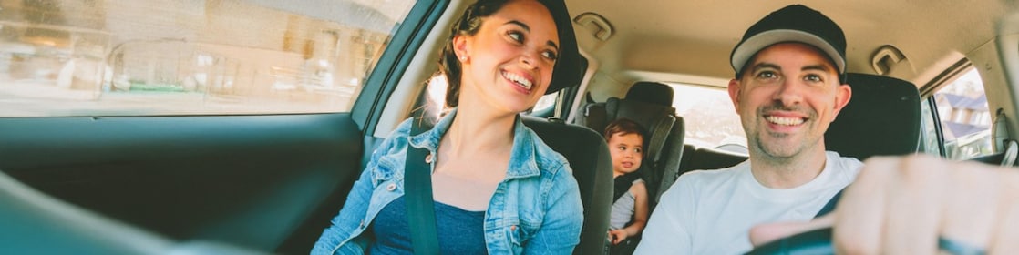 Family of three: woman, men and baby in car set inside a car