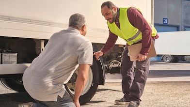 Truck parks with two main talking near truck tire