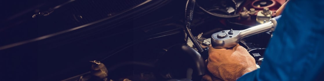 Mechanic’s hand tightening an engine part with a wrench.