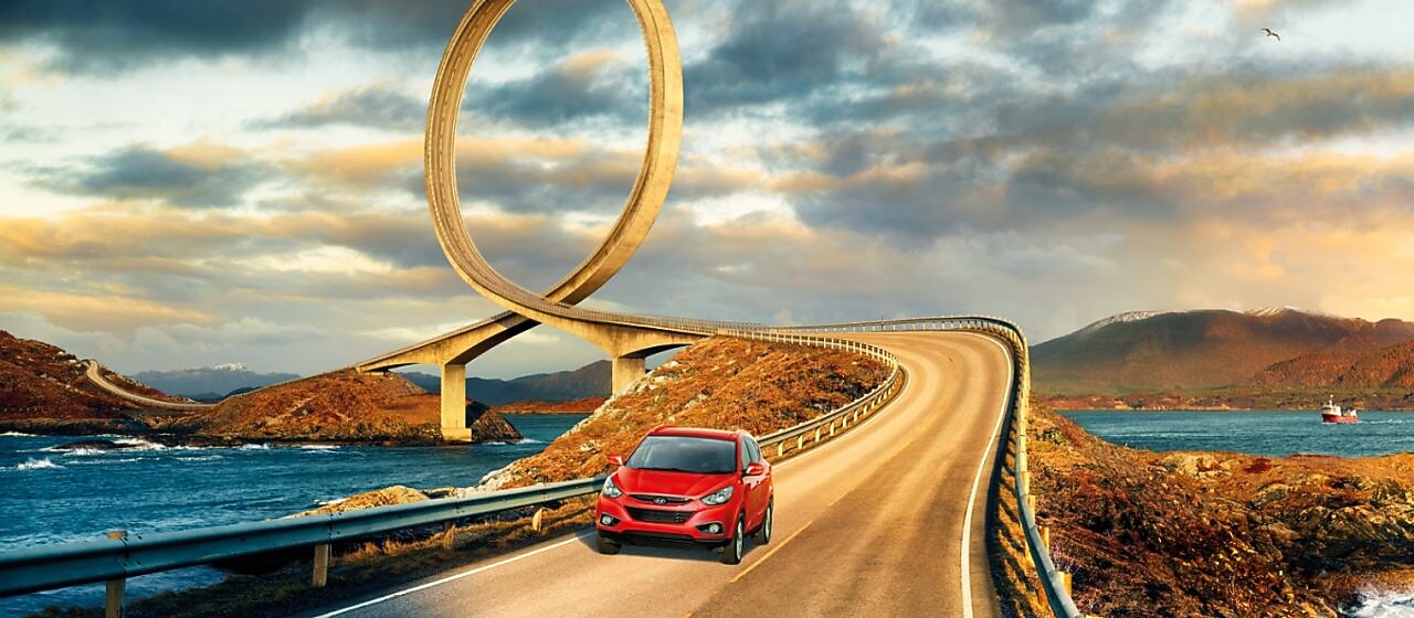 Red car driving on the road by the river