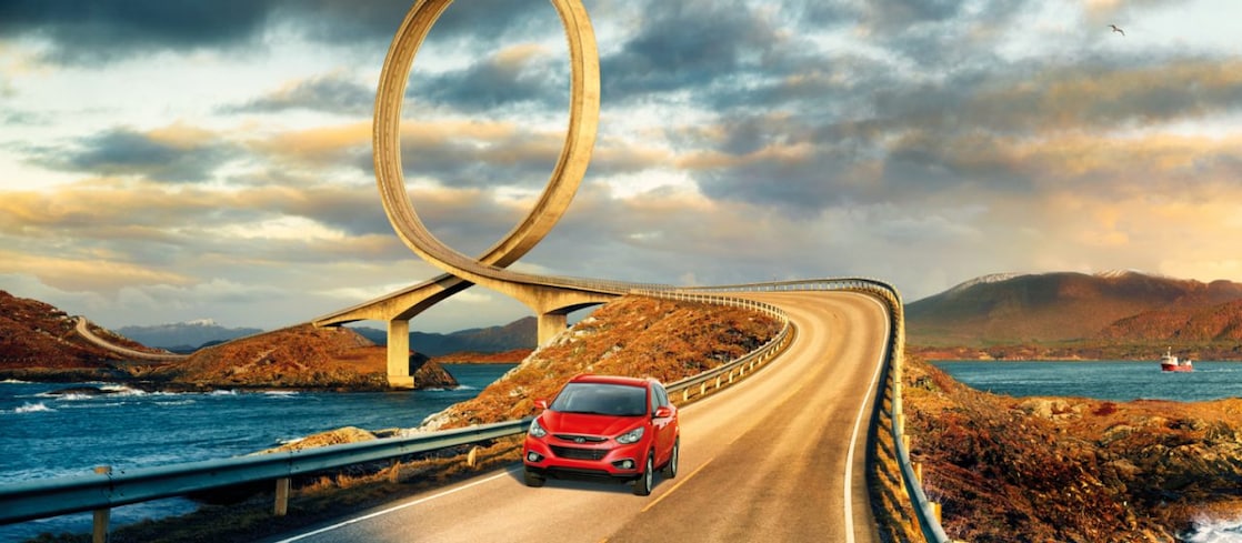 Red car driving on the road by the river