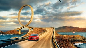 Red car driving on the road by the river