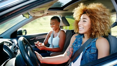 Dos mujeres sentadas en los asientos delanteros de un auto.