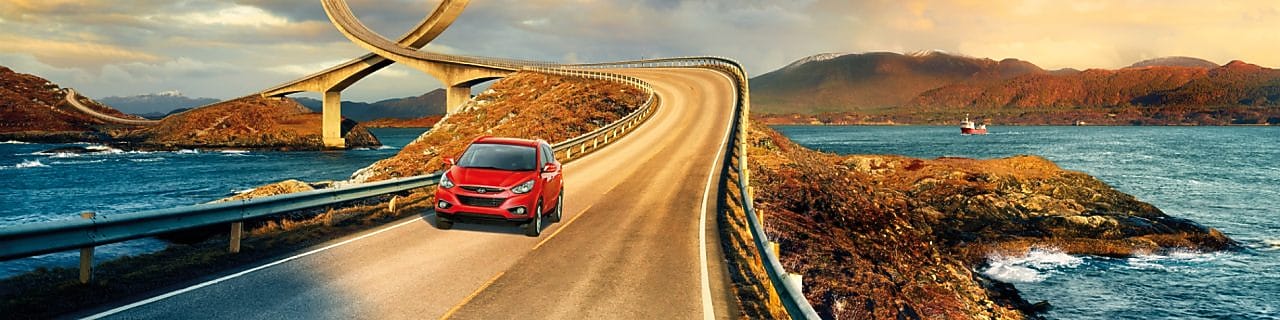 Auto rojo circulando por la ruta junto al río